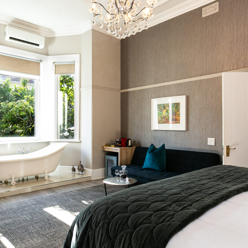 This is an elegant luxury hotel bedroom with elegant decor. A standout feature is a freestanding clawfoot bathtub.